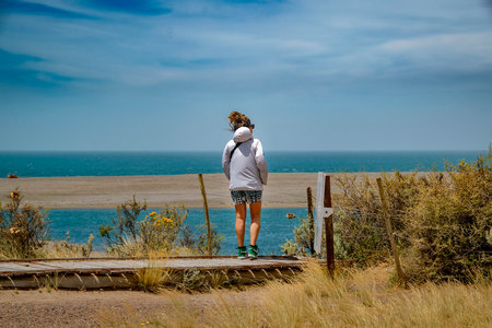 Peninsula Valdes, Argentina; December 29 2022: Young woman at viewpoint watching wildlife marine at peninsula valdes, viedma department, chubut province, argentinaの写真素材