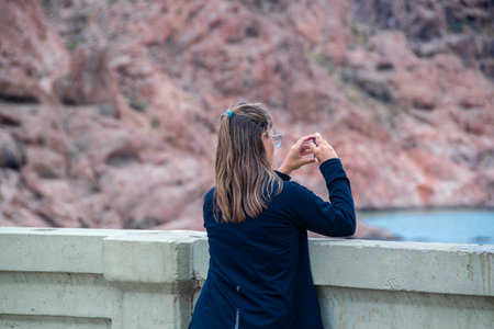 Woman taking photos at border of bridge in florentino ameghino dam, a gravity dam in chubut province, patagonia, argentinaの写真素材
