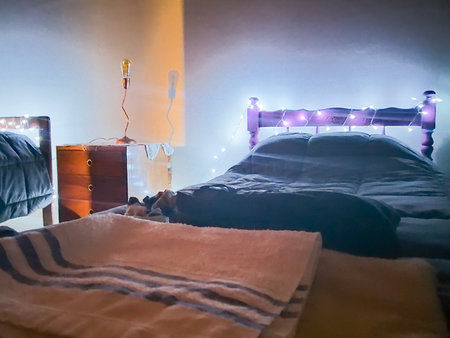 Interior night scene of kids room decorated with christmas artificial light surrounded the head of bedの写真素材