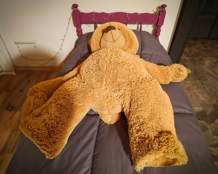 High angle interior view scene of big brown teddy bear lying at kids bedの写真素材