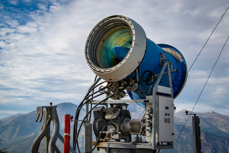 A large snow cannon positioned outdoors in a mountainous area under a cloudy sky, used to create artificial snow on ski slopes, san carlos de bariloche, rio negro province, argentinaの写真素材