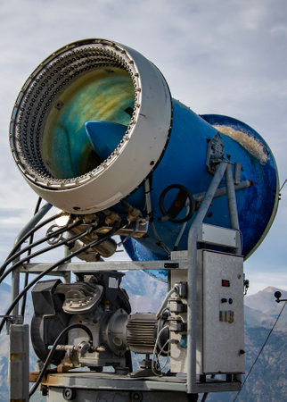 A large snow cannon positioned outdoors in a mountainous area under a cloudy sky, used to create artificial snow on ski slopes, san carlos de bariloche, rio negro province, argentinaの写真素材