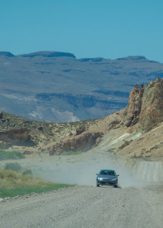 Dirt road crossing rocky mountains landscape at piedra parada, an ancient volcanic environment located in patagonia, chubut province, argentinaの写真素材