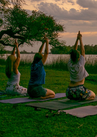 Heterogeneous women small group practicing kundalini yoga at border of river, santa lucia river, los cerrillos, canelones department, uruguayの写真素材
