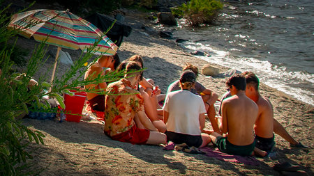 San Carlos de Bariloche, Argentina; January 5 2023: Group of teenaggers enjoying a sunny summer day at one of the beaches of bariloche, the most famous patagonian vacations site, rio negro province, argentina.の写真素材