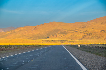 Empty highway and rocky mountain at golden hour time patagonian landscape, rio negro province, argentinaの写真素材
