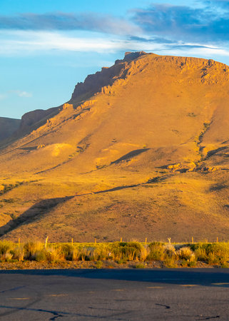 Empty highway and rocky mountain at golden hour time patagonian landscape, rio negro province, argentinaの写真素材