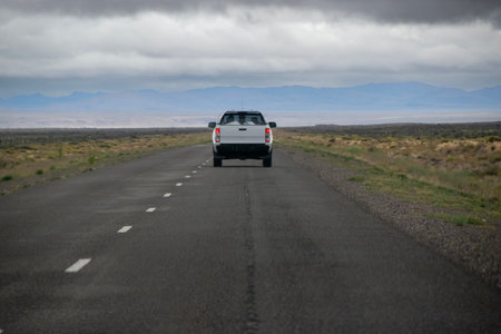 Van crossing highway surrounded by arid steppe patagonia landscape, chubut province, patagonia, argentinaの写真素材