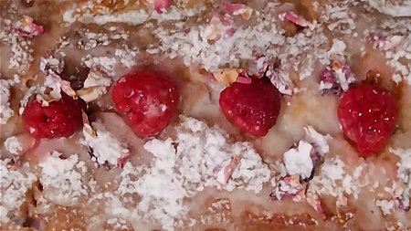 High angle view loaf-shaped cake with a golden-brown crust, topped with powdered sugar and...