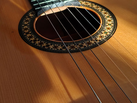 Close-up, high-angle detail shot of a classic spanish guitar, showcasing its wood texture and elegant craftsmanship.の写真素材