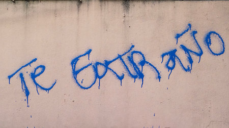 Front view of a graffiti message reading in spanish language âte extraÃ±oâ âI miss youâ written in blue on a textured pink wall.の写真素材