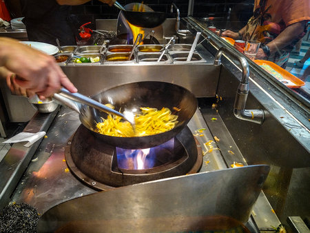 Medium shot, eye-level image of a person cooking french fries in a pan at a street food stand.の写真素材