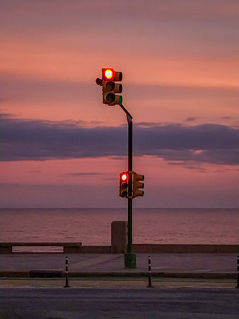 Traffic light glowing at sunset by the sea at boardwalk, montevideo city, uruguayの写真素材