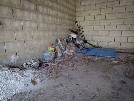 Wide shot of a makeshift bed in an abandoned corner with garbage and broken bricks.の写真素材