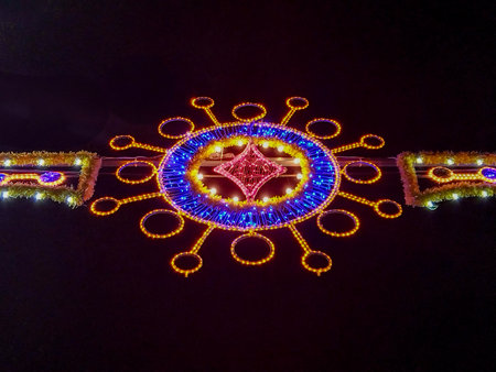 Close-up, low angle of a colorful illuminated street decoration shaped like a sunburst with neon lights, taken at night.の写真素材