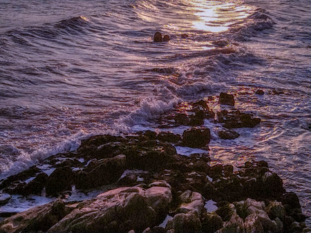A high angle view capture of sea waves crashing on rocks at golden hour.の写真素材