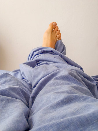 Medium shot from a slightly high angle showing a pair of bare feet poking out from beneath a blue...
