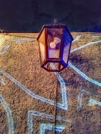 Low angle view shot picture of a lantern hanging on a wall, illuminated by soft lightの写真素材