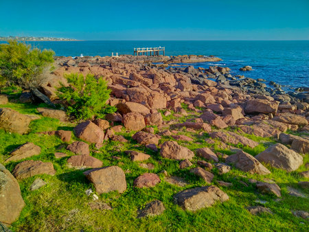 An eye-level, medium shot of a rugged, rocky coastline under a clear blue sky.の写真素材
