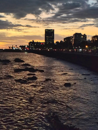 A wide shot captures a dimly lit urban skyline at dusk, with buildings silhouetted against a fading sky, montevideo city, uruguayの写真素材