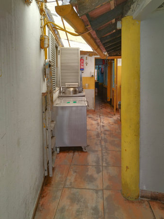 Frontal view of a narrow corridor with aged wooden flooring and bright ceiling lights, leading to distant roomsの写真素材