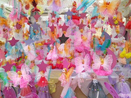 Frontal close-up of a vibrant stall filled with fantasy dolls dressed in pink and pastel tonesの写真素材