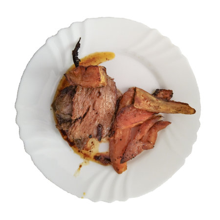 Overhead shot of an oven-roasted meat dish served with sweet potatoes on a white plateの写真素材