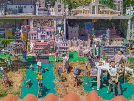 Close-up of a colorful handcrafted diorama with tiny human figures engaged in town life, surrounded by small buildings and elements of daily activityの写真素材