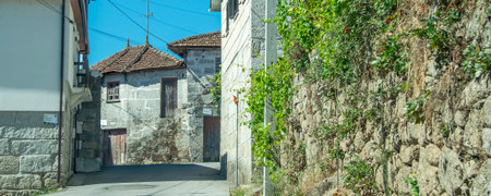 Frontal view of a narrow village street lined with traditional stone walls and whitewashed houses.の写真素材