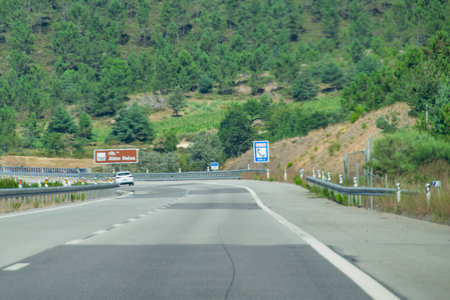 Empty asphalt highway curving gently through a forested hilly landscape under natural daylight, alem relvas, portugalの写真素材