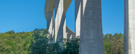 Low-angle shot of a tall concrete viaduct bridge extending across a forested landscape, vila real, portugalの写真素材
