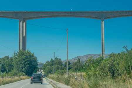 Low-angle shot of a tall concrete viaduct bridge extending across a forested landscape, vila real, portugalの写真素材