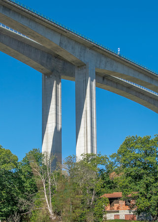 Low-angle shot of a tall concrete viaduct bridge extending across a forested landscape, vila real, portugalの写真素材