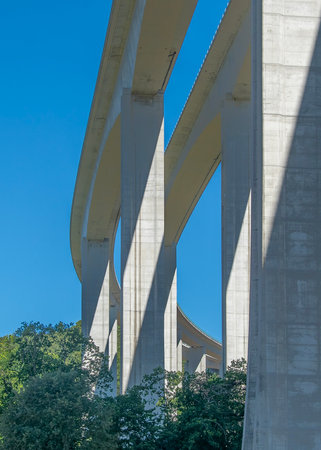 Low-angle shot of a tall concrete viaduct bridge extending across a forested landscape, vila real, portugalの写真素材
