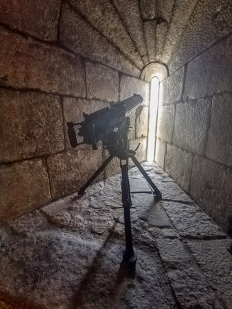 Narrow stone corridor with a small cannon pointed toward a vertical slit in the wall, castle of...