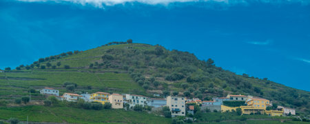 High-angle, long shot of a traditional Portuguese village, nestled in green hilly landscape under sunny sky.の写真素材
