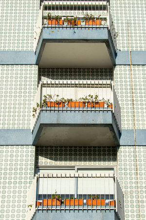 Low angle front view of a modern apartment building featuring repeating balcony patterns and orange planters.の写真素材