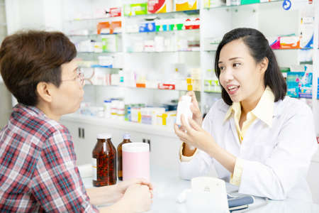 Beautiful asian pharmacist advice about medicine to female customer in drugstoreの写真素材