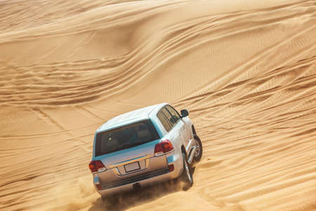 Landcruiser driving up a sand duneの写真素材