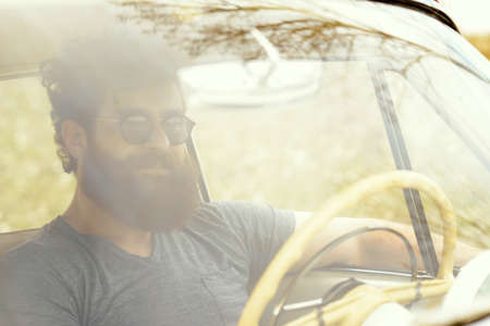 Bearded man behind the wheel of a retro car