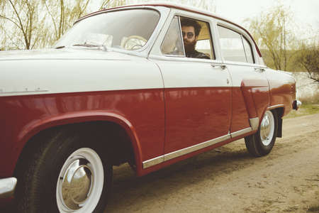 Man with beard driving a retro car
