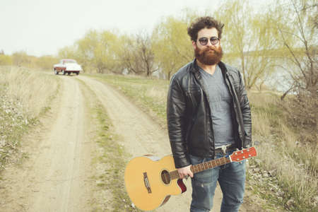 Bearded man playing guitar, near retro carの写真素材