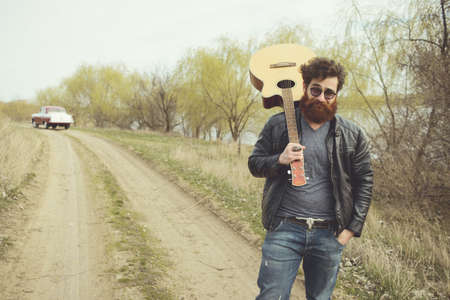 Bearded man playing guitar, near retro carの写真素材