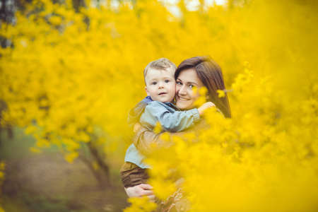 Mother and son happy in the park, near yellow flowers
