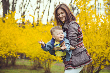 Mother and son happy in the park, near yellow flowersの写真素材