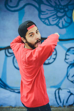 Young man  dances with a graffiti in the backgroundの写真素材