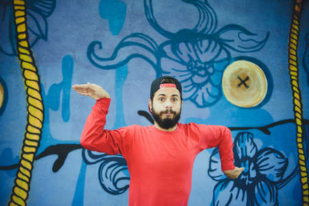 Young man  dances with a graffiti in the backgroundの写真素材