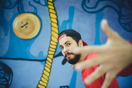 Young man  dances with a graffiti in the backgroundの写真素材