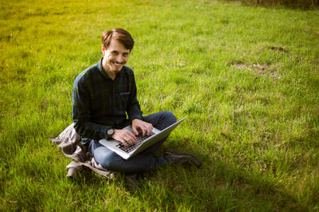Man with laptop on the lawnの写真素材