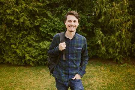 Young guy with a backpack in the park, green backgroundの写真素材